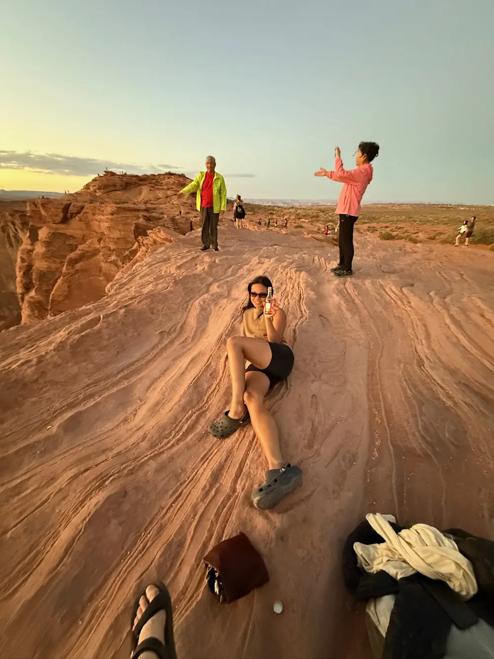 Gaby Luong relaxing on red sandstone at sunset, raising a small bottle